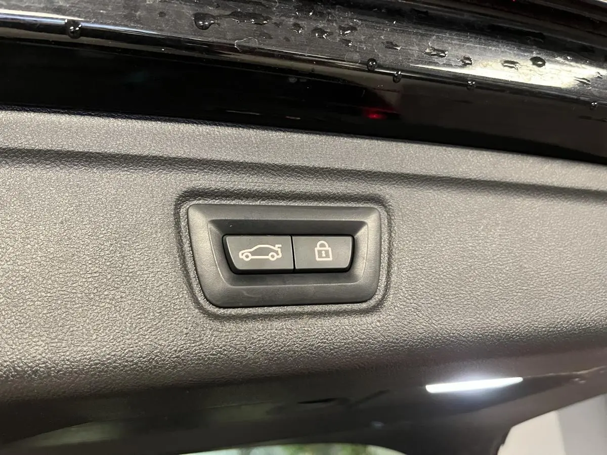 Boutons d'ouverture et de verrouillage du coffre sur la partie intérieure du hayon noir d'une BMW Série 3 Touring.