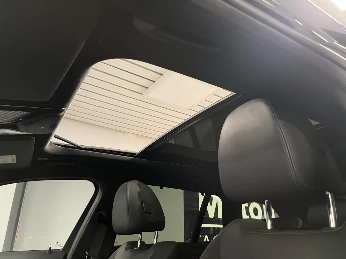 Toit ouvrant panoramique en verre vu de l'intérieur avant de la BMW Série 3 Touring noire 320e M Sport 2022