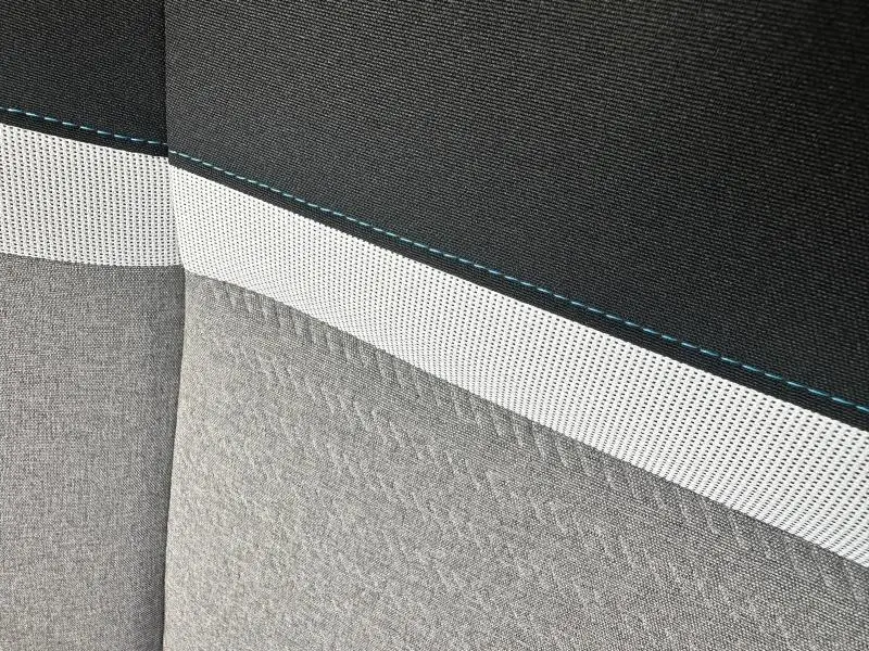 Détail du tissu gris clair et noir avec surpiqûres bleues sur la banquette arrière du Citroën Berlingo XL 2024.