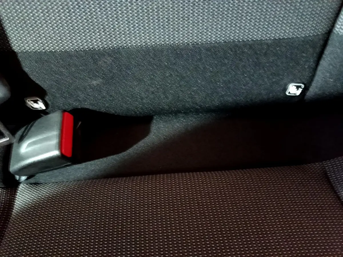 Gros plan sur la banquette arrière noire de la Citroën C3 avec boucle de ceinture de sécurité rouge visible.