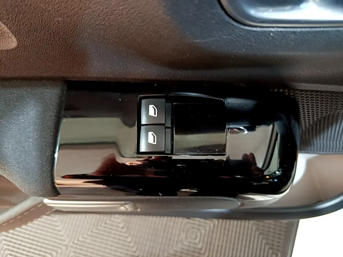 Gros plan sur les commandes de lève-vitres électriques côté conducteur dans l’habitacle noir de la Citroën C3 blanche.