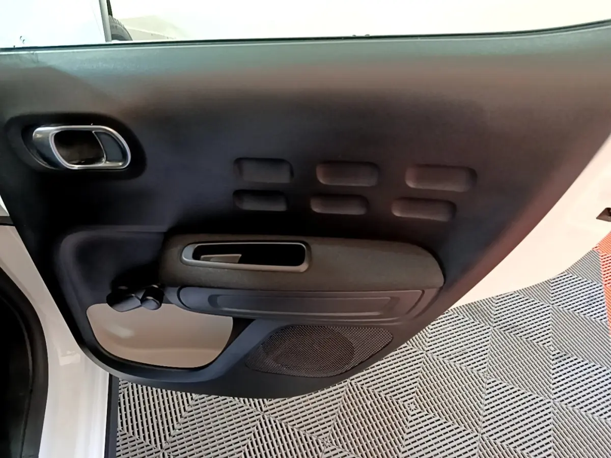 Vue rapprochée de la porte avant gauche intérieure noire et beige d’une Citroën C3 blanche de 2020.