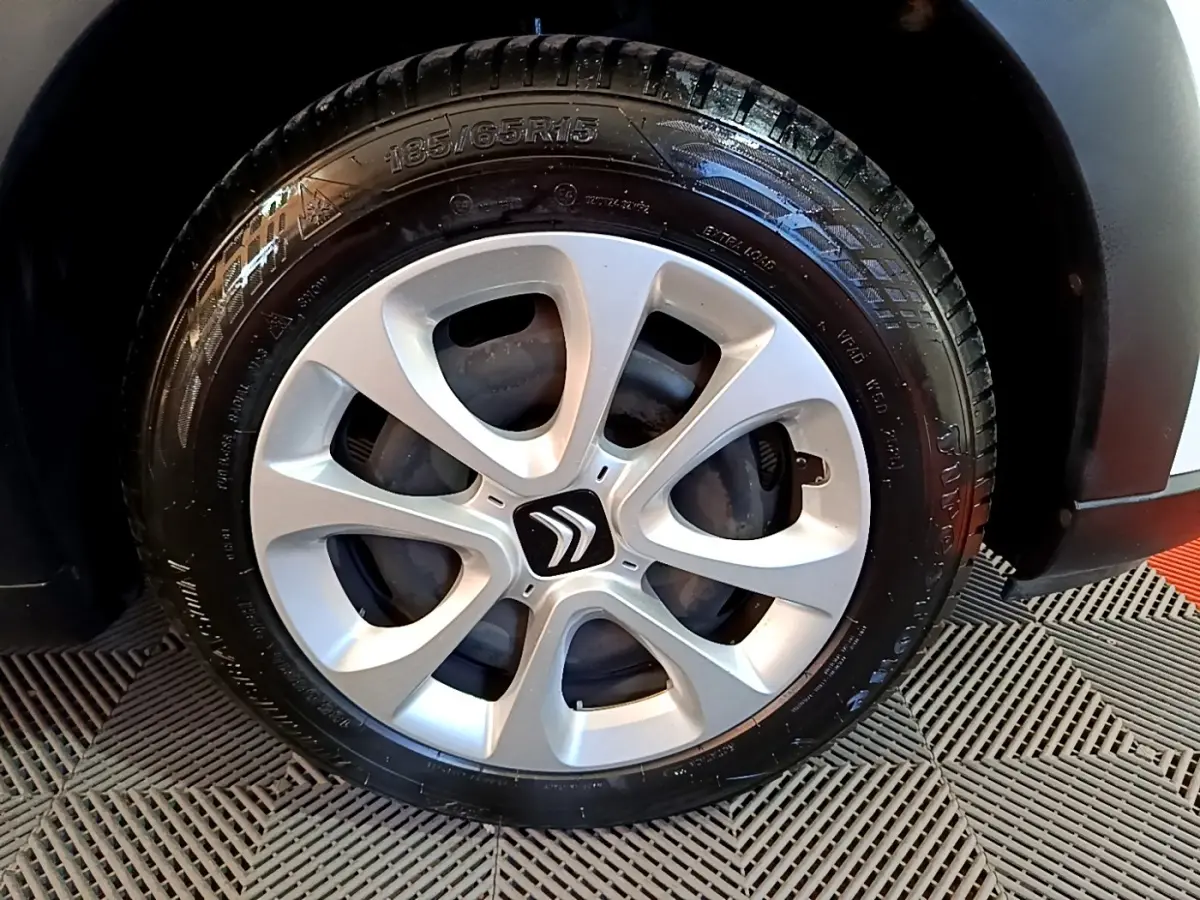 Gros plan sur la roue avant droite d'une Citroën C3 blanche, mettant en valeur la jante argentée au design moderne.