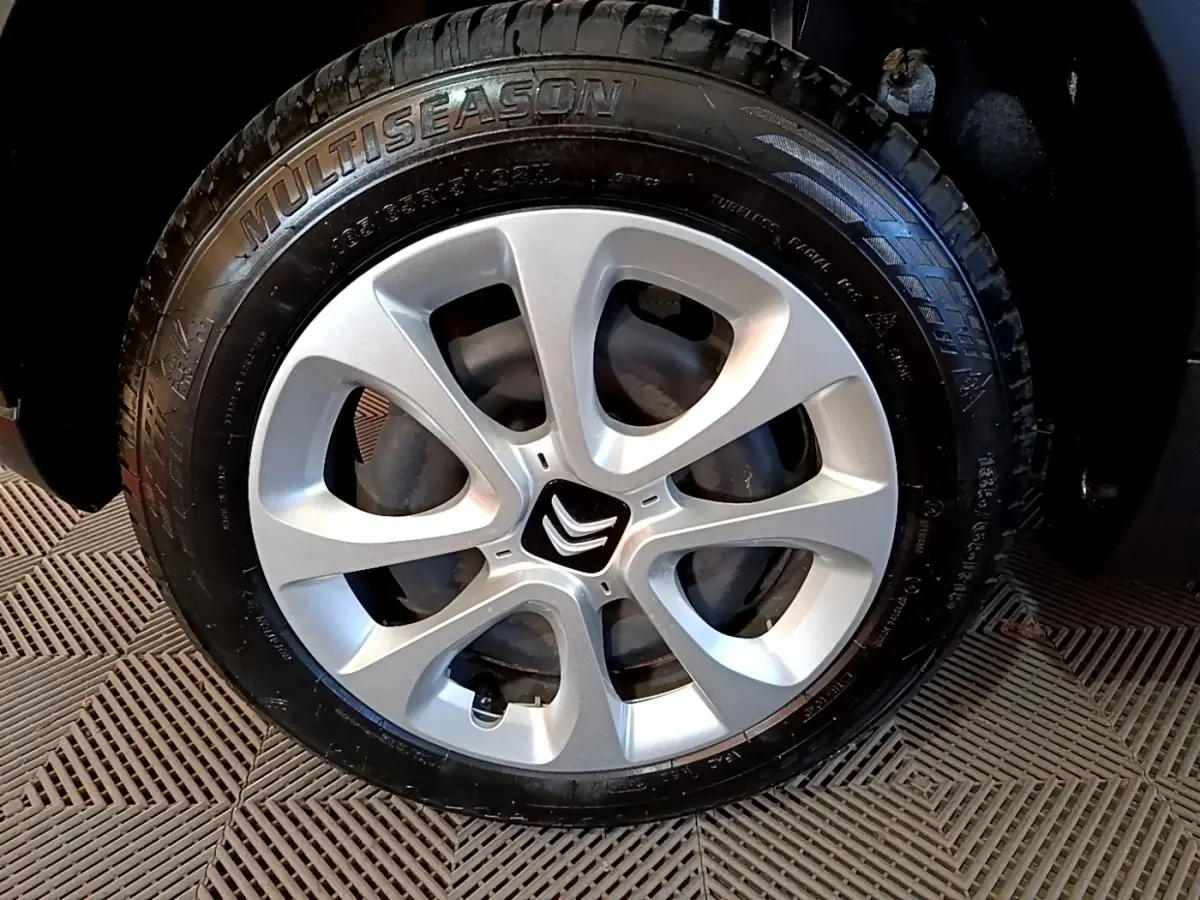 Gros plan sur la roue avant droite de la Citroën C3 blanche, avec jante argentée et logo Citroën central.