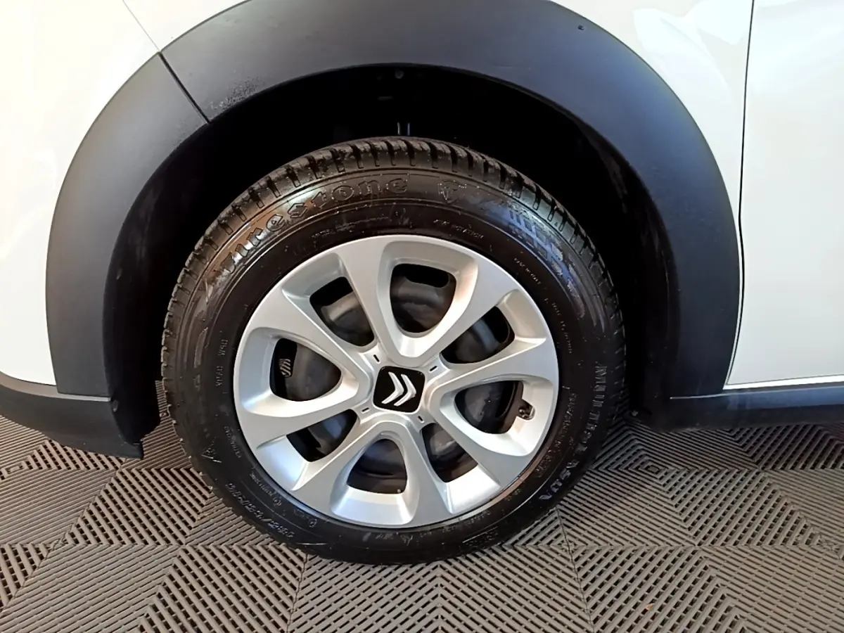 Gros plan sur la roue avant gauche d'une Citroën C3 blanche avec jante alliage et passage de roue noir mat.