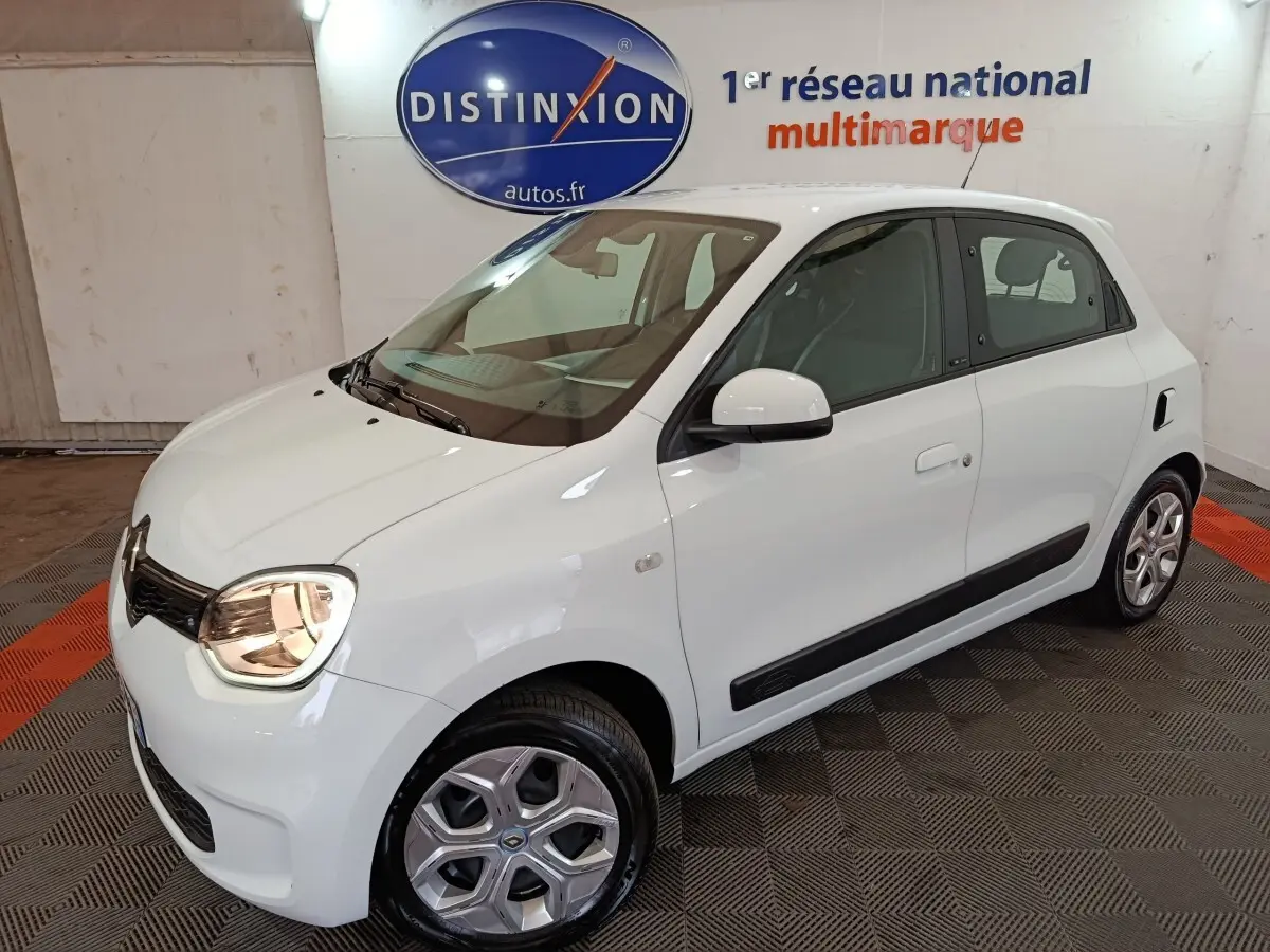 Vue 3/4 avant droite d'une Renault Twingo Zen blanche électrique, avec poignées et rétroviseurs assortis.