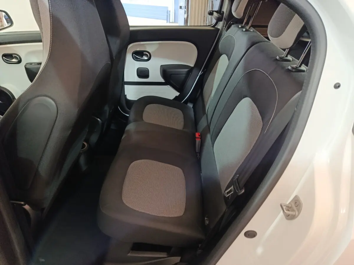 Vue intérieure arrière côté droit de la Renault Twingo Zen blanche, montrant la banquette 2 places avec sièges bicolores gris et noir.
