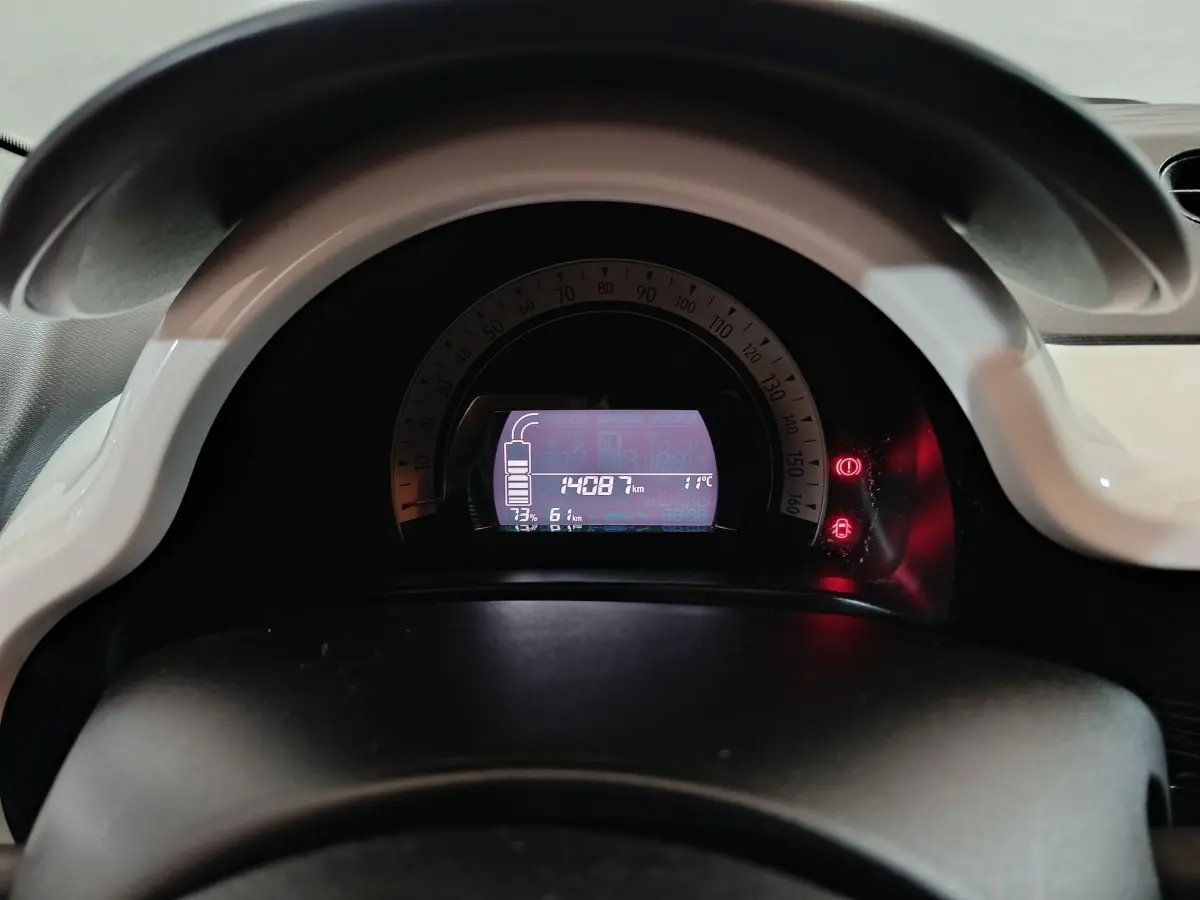Vue rapprochée du tableau de bord numérique de la Renault Twingo Zen 2021 avec affichage kilométrique et indicateurs lumineux rouges.
