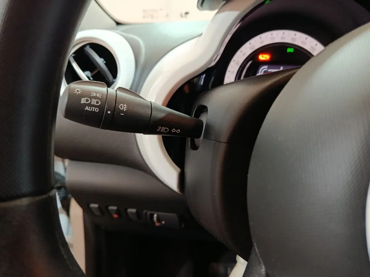 Gros plan sur la commande des phares et clignotants à gauche du volant dans l’habitacle blanc de la Renault Twingo Zen électrique 2021.