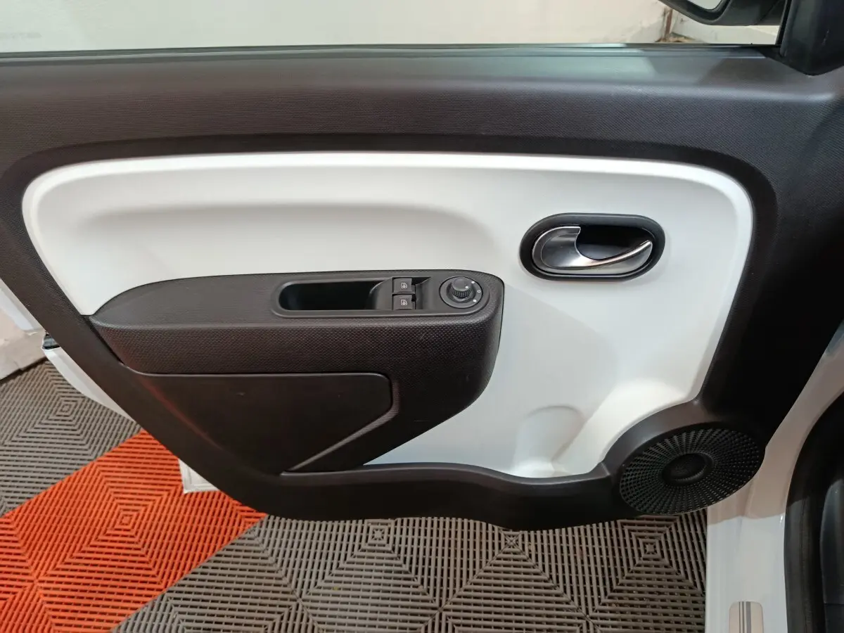 Vue intérieure du panneau de porte avant gauche de la Renault Twingo Zen blanc, avec commandes électriques et haut-parleur intégré.