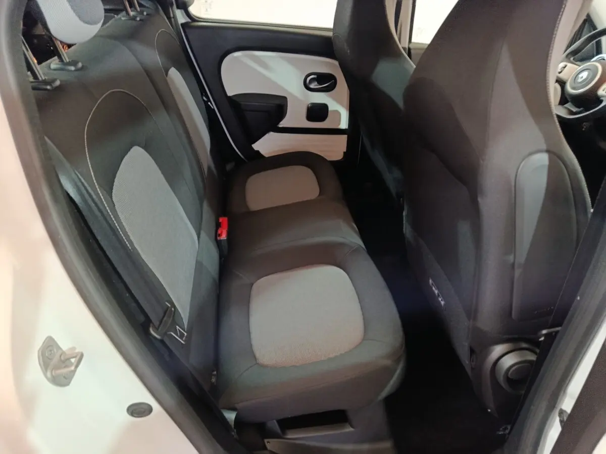 Vue intérieure sur la banquette arrière grise et noire de la Renault Twingo Zen blanche, côté gauche avec porte ouverte.