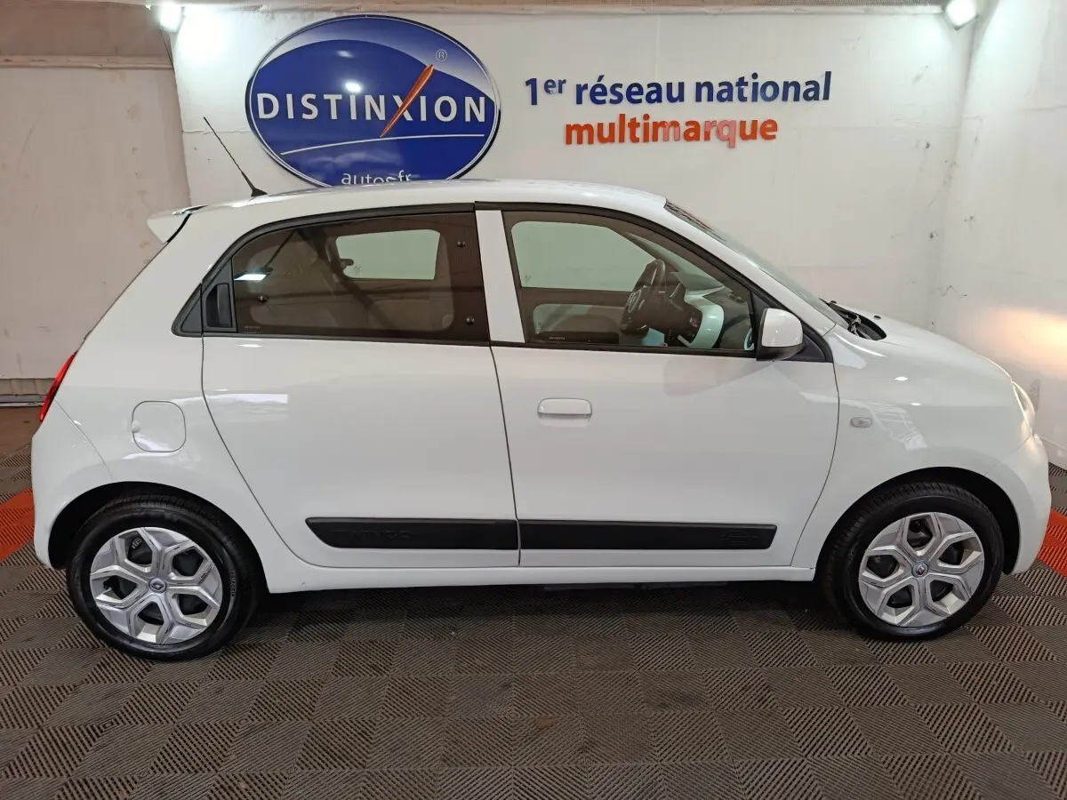 Profil droit d'une Renault Twingo Zen blanche de 2021, compacte avec poignées et bas de porte noirs, roues alliage.