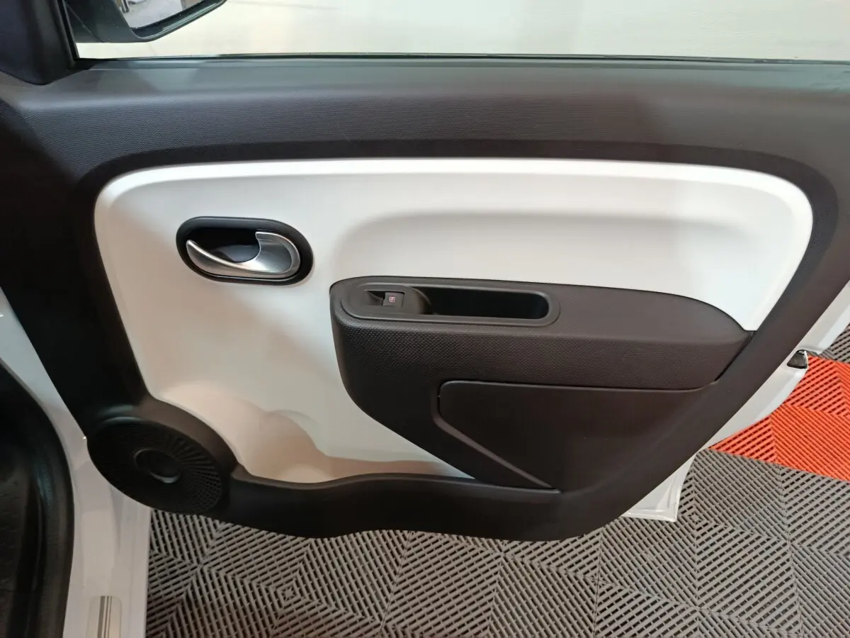 Vue intérieure côté gauche de la porte blanche de la Renault Twingo Zen 2021 avec poignée argentée et haut-parleur noir.