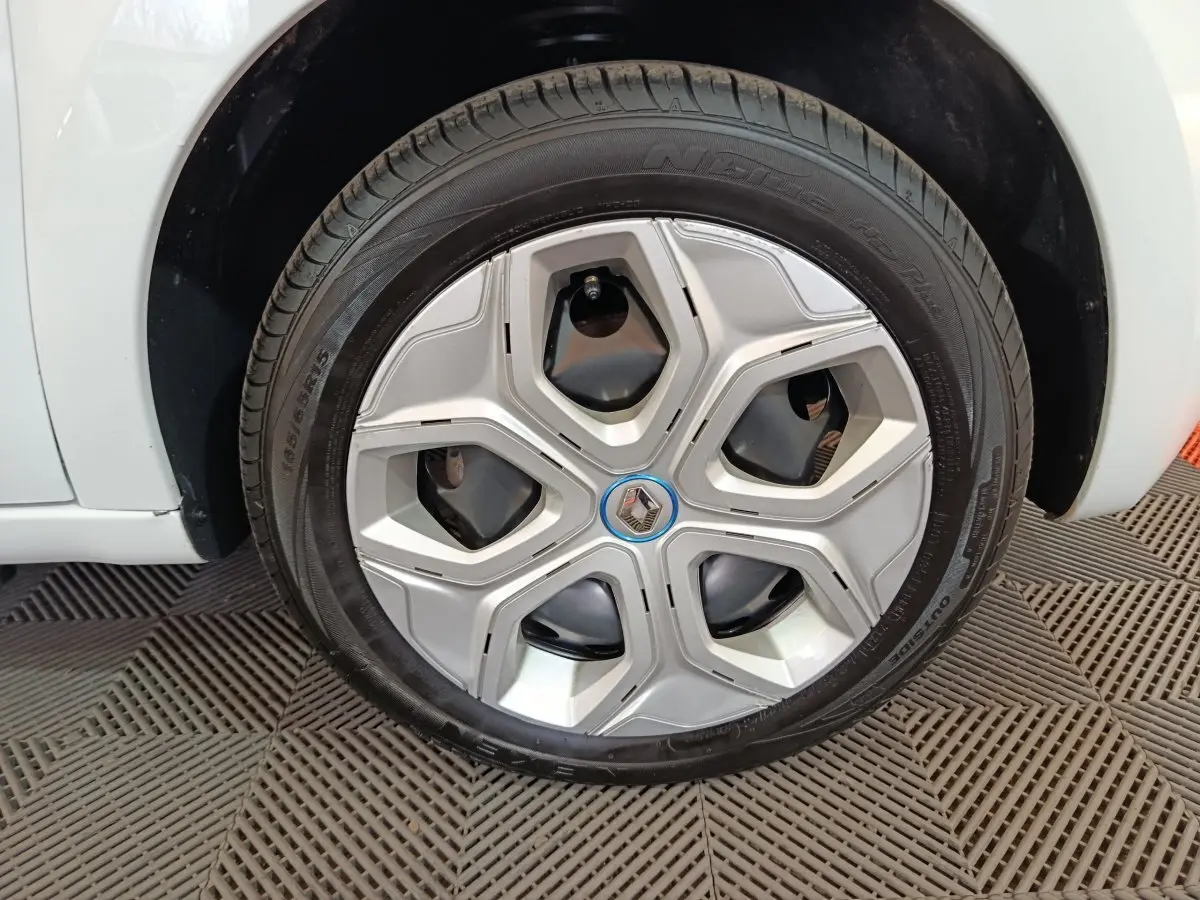 Vue rapprochée de la roue arrière droite d'une Renault Twingo Zen blanche de 2021, sur sol texturé.