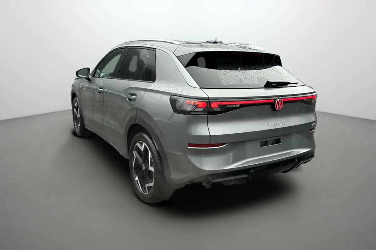 Volkswagen T-Roc gris loup en 3/4 arrière droit, avec feux arrière LED et jantes alu 18 pouces noires.