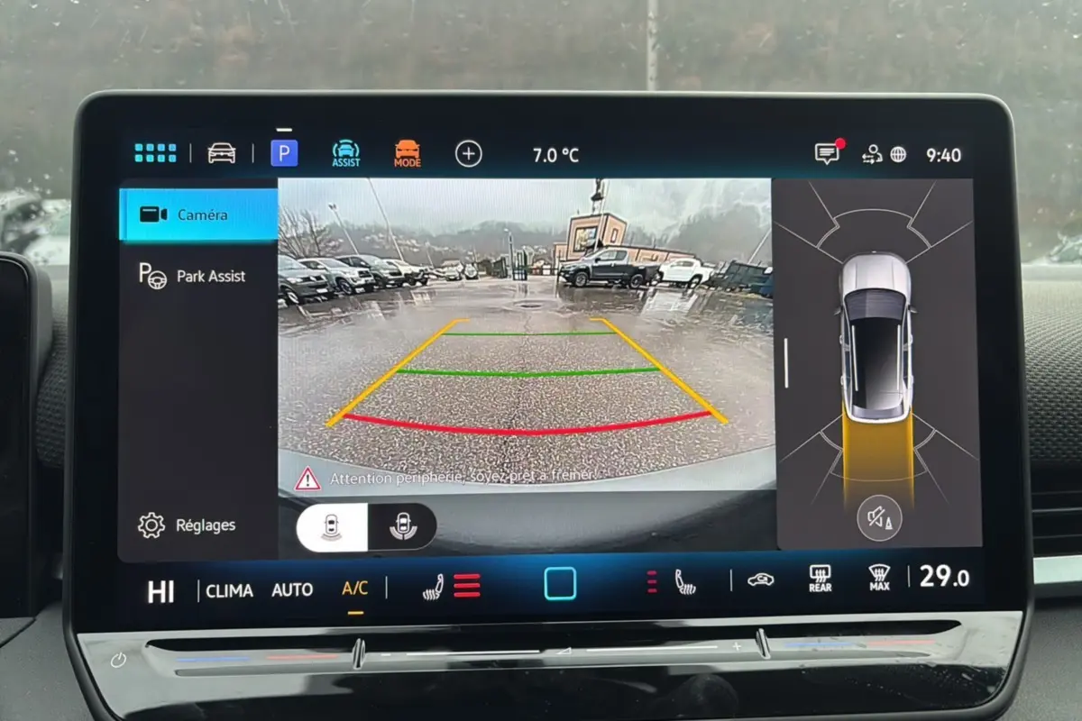 Écran de caméra de recul du Volkswagen T-Roc gris loup, affichant l'aide au stationnement sous la pluie.