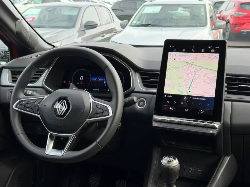 Vue intérieure du tableau de bord du Renault Captur 2025 avec volant multifonction et écran tactile central affichant la navigation.