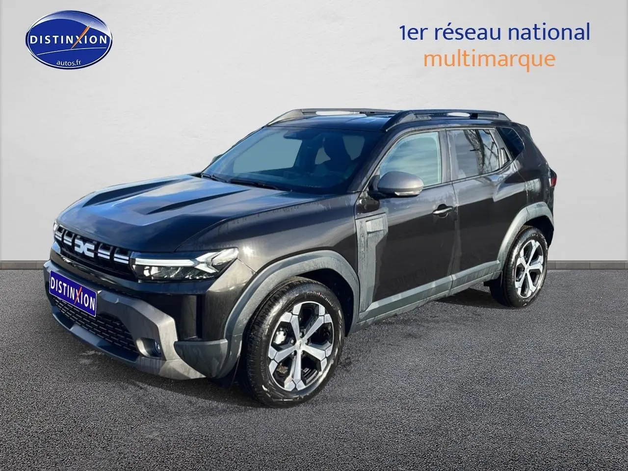 Dacia Duster noir vue 3/4 avant droit, avec jantes alu et barres de toit visibles sur fond neutre.