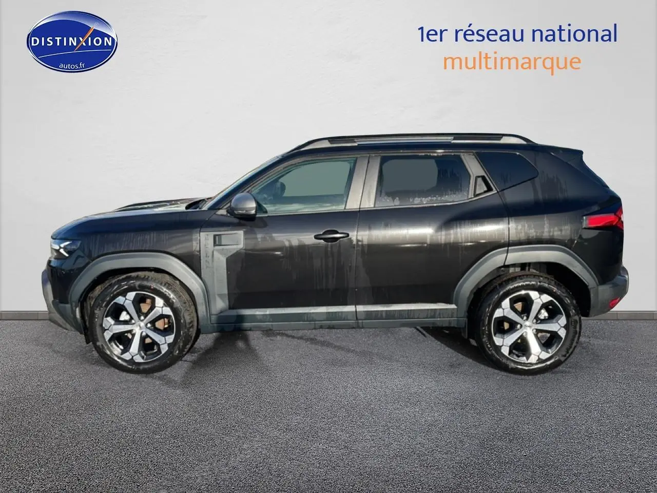 Profil côté gauche du Dacia Duster noir 2026 avec jantes alu et barres de toit visibles.