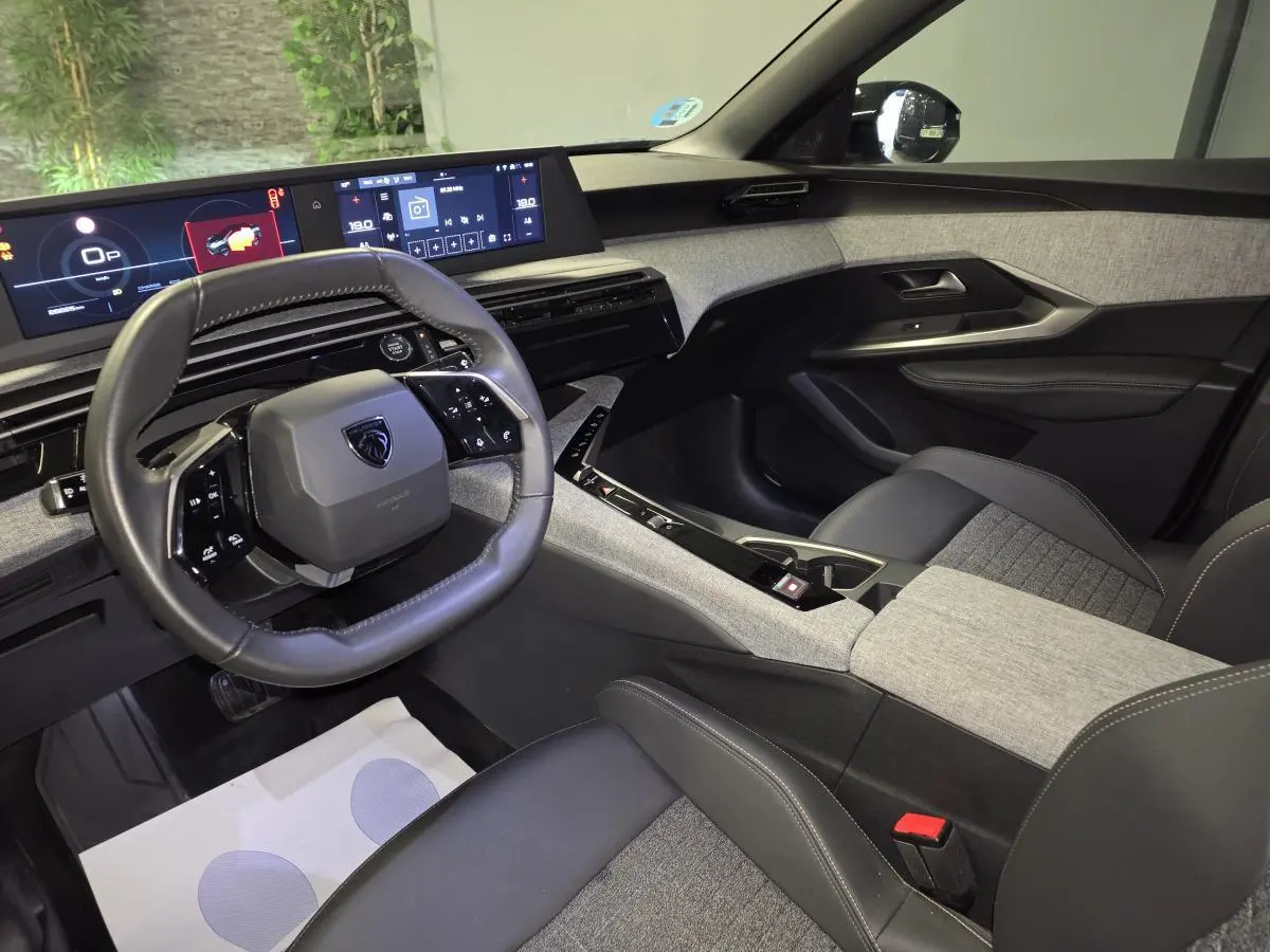 Intérieur avant droit du Peugeot 3008 2025 hybride, avec tableau de bord numérique et sellerie tissu gris et noir.