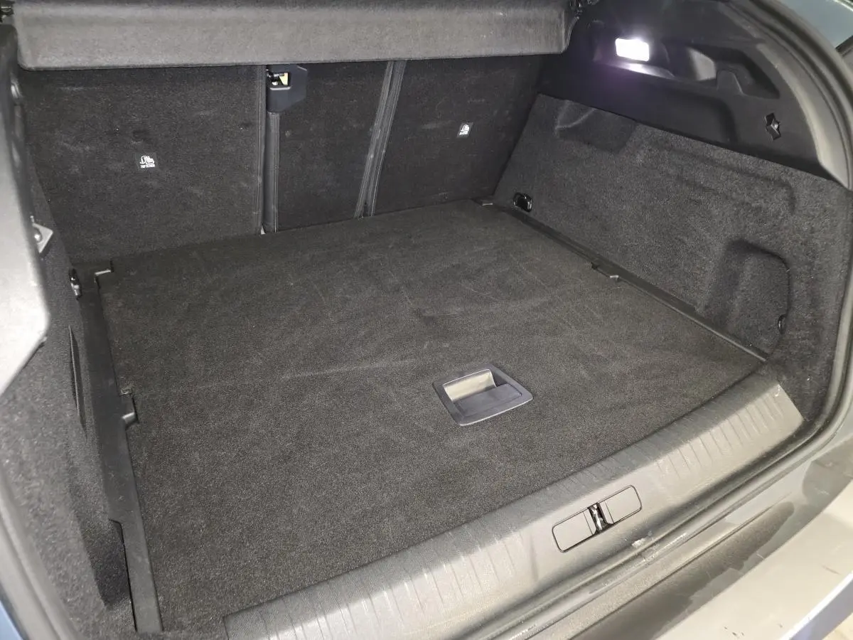 Coffre spacieux du Peugeot 3008 bleu, vue intérieure arrière avec tapis noir et éclairage LED intégré.