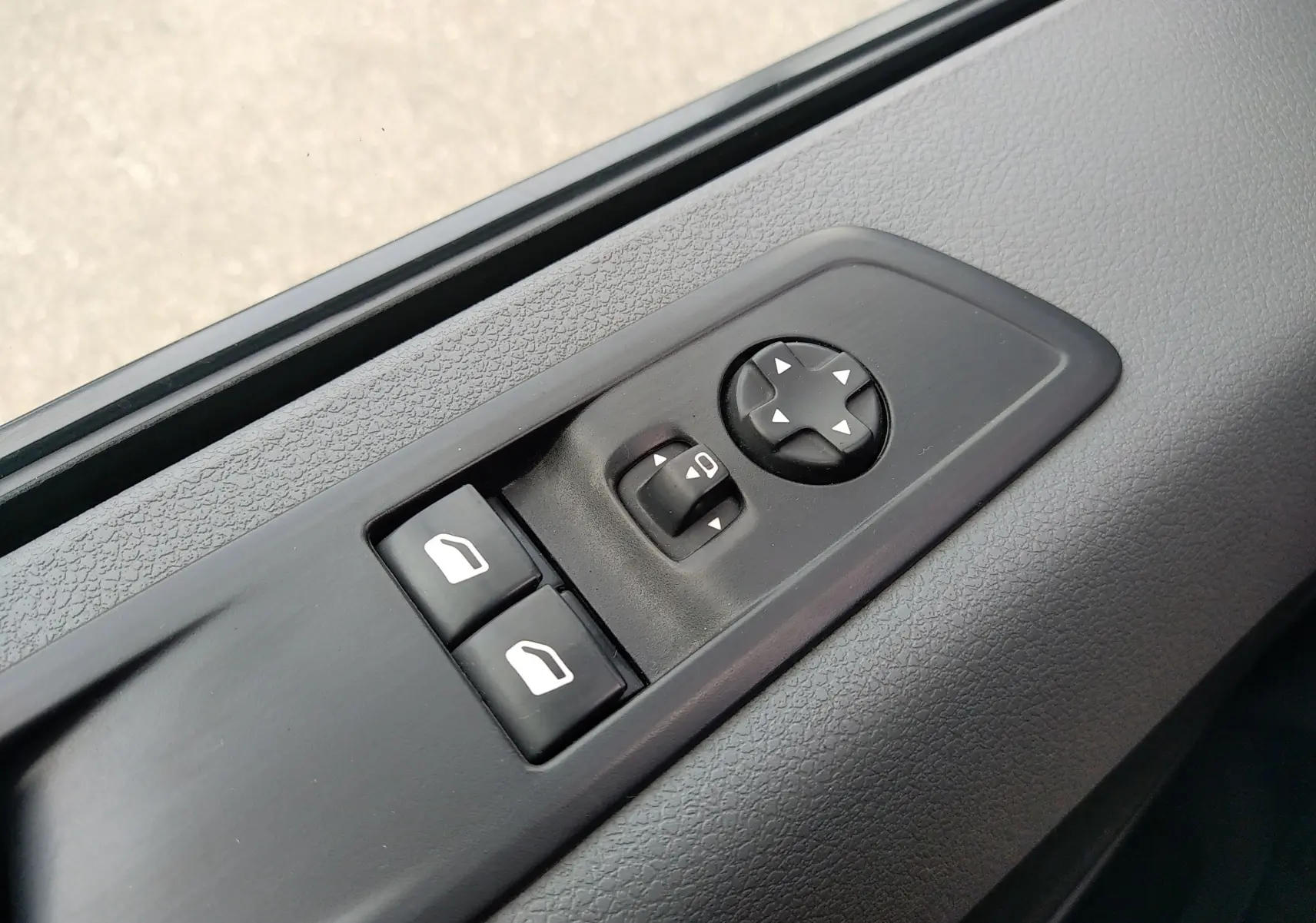 Gros plan sur les commandes électriques des vitres et des rétroviseurs côté conducteur du Peugeot Expert Fourgon blanc de 2020.