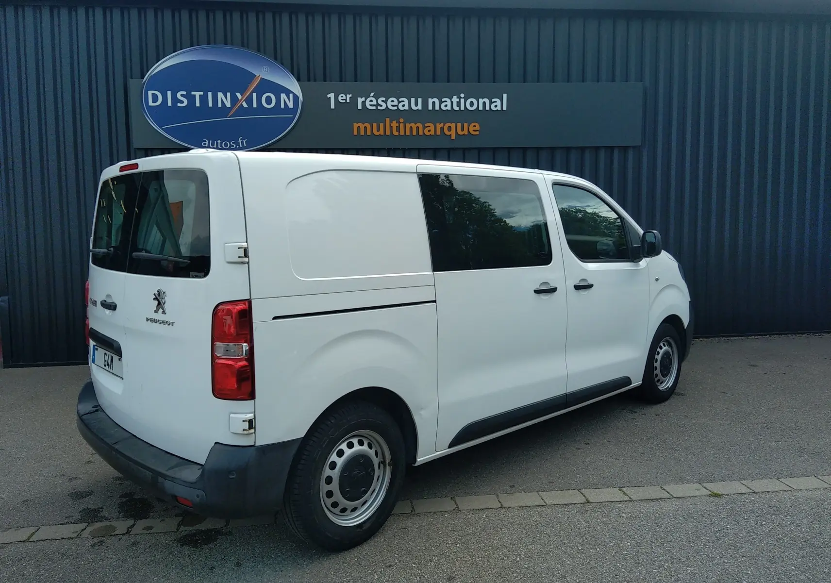 Vue 3/4 arrière côté droit d'un Peugeot Expert Fourgon blanc uni avec vitres teintées arrière et jantes acier.