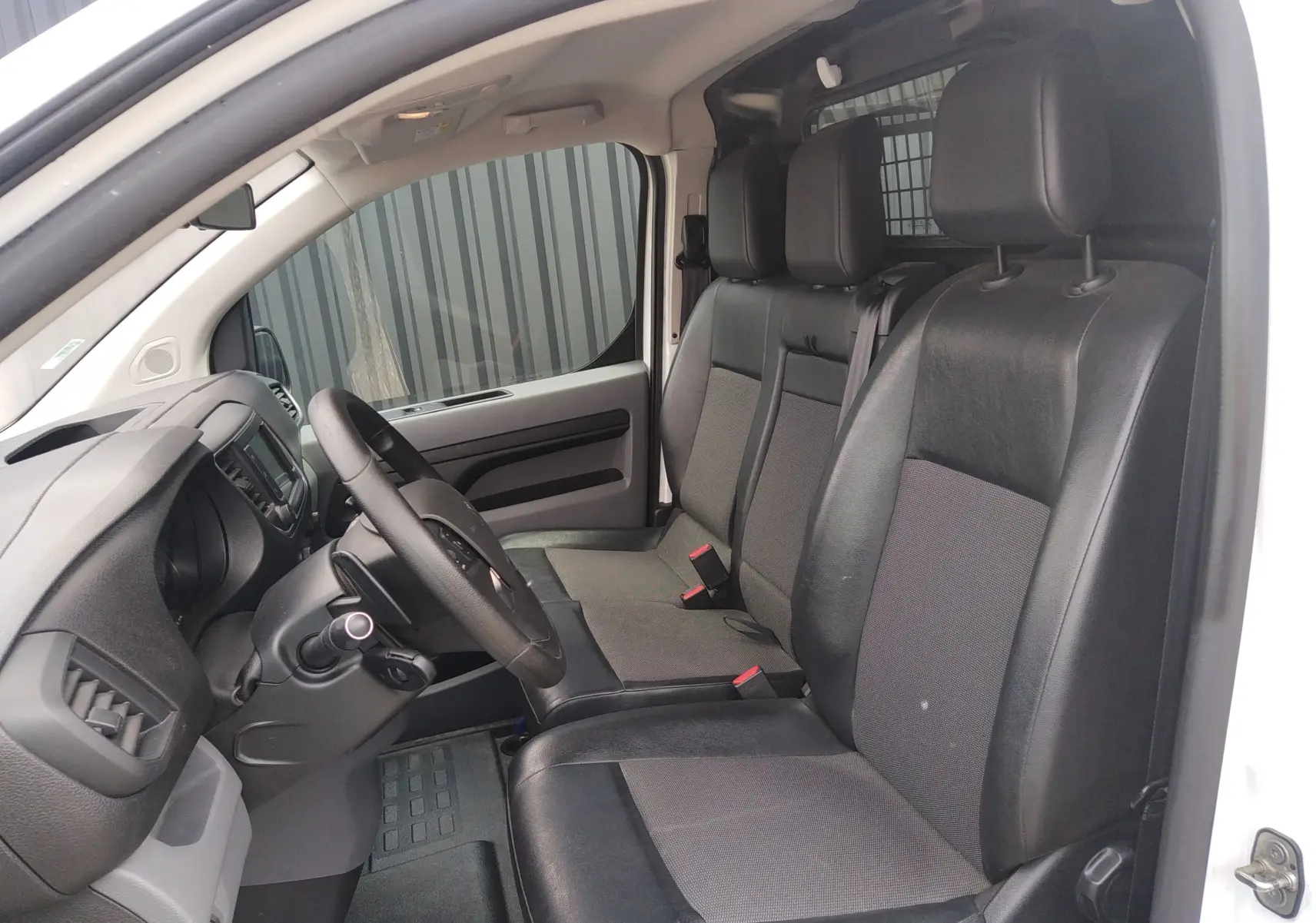 Intérieur du Peugeot Expert Fourgon 2020, vue côté conducteur, sièges avant en tissu et cuir noir, tableau de bord visible.