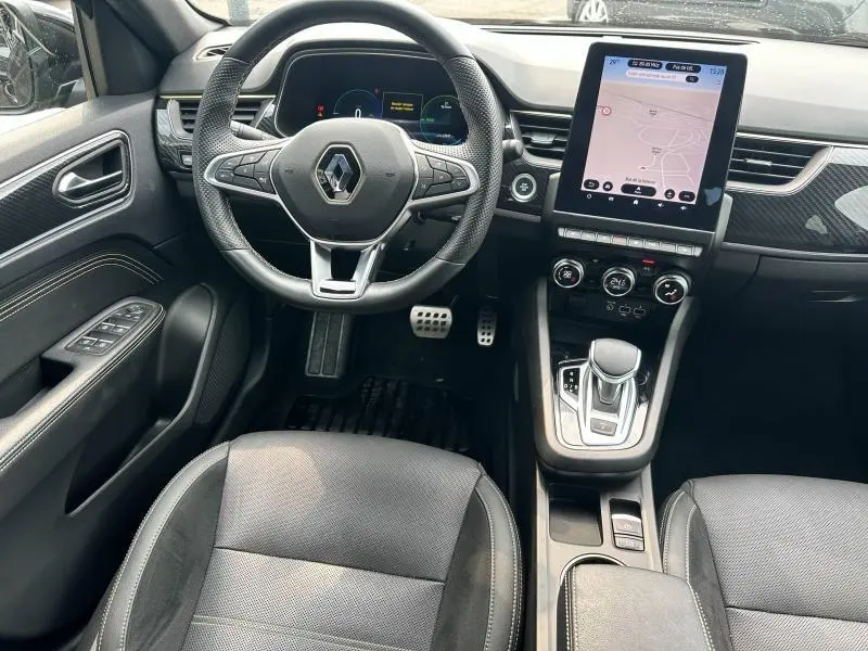 Intérieur noir du Renault Arkana 2023, vue du poste de conduite avec volant multifonction et écran tactile vertical.