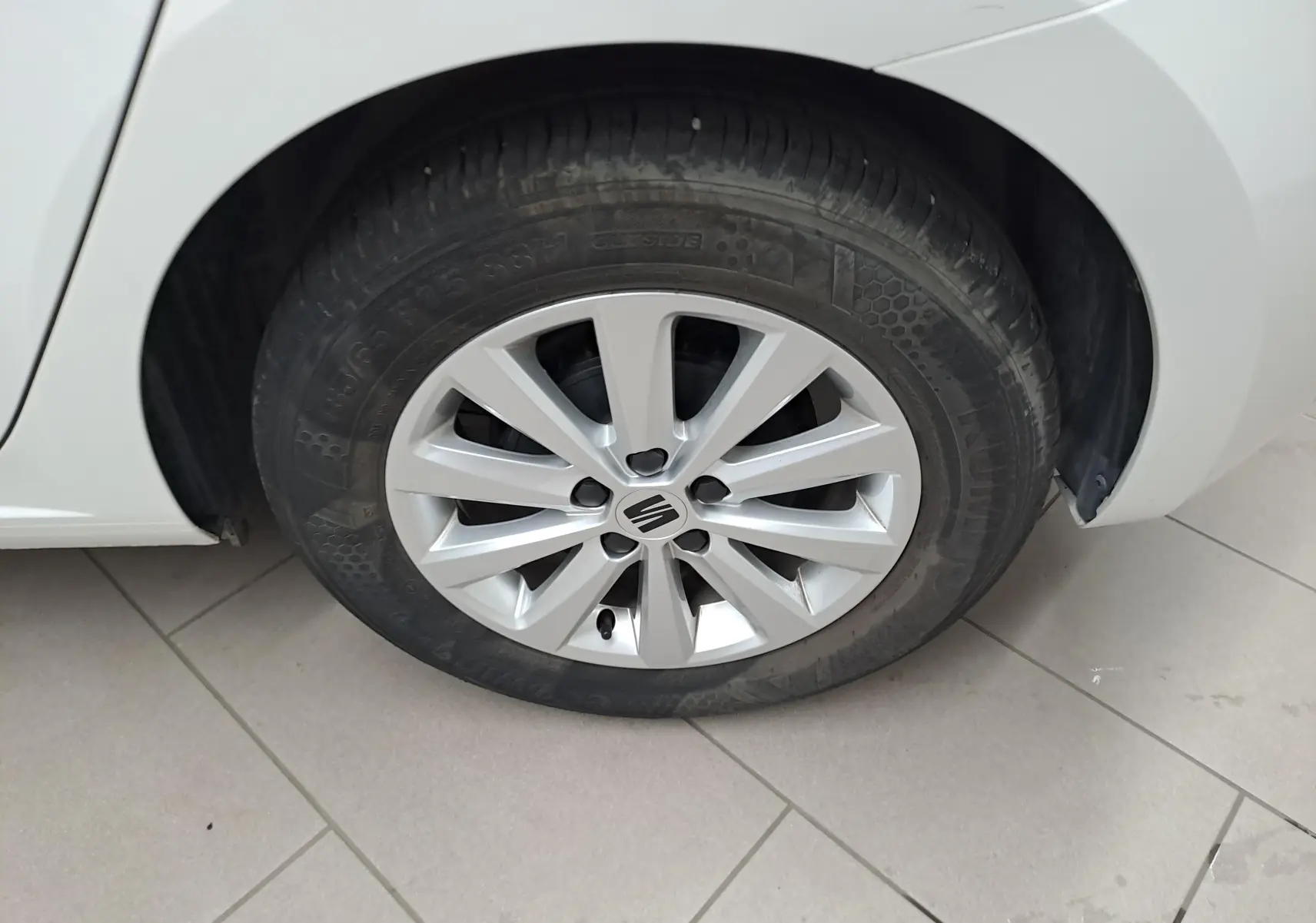 Gros plan sur la roue avant gauche blanche d'une SEAT Ibiza 2023 avec jante argentée et logo central visible.