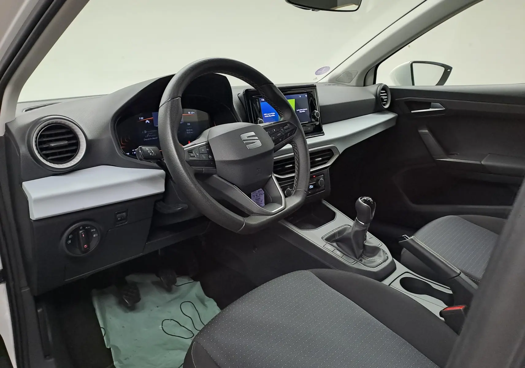 Intérieur côté conducteur de la SEAT Ibiza 2023 blanc candy, volant multifonction et boîte manuelle visible.