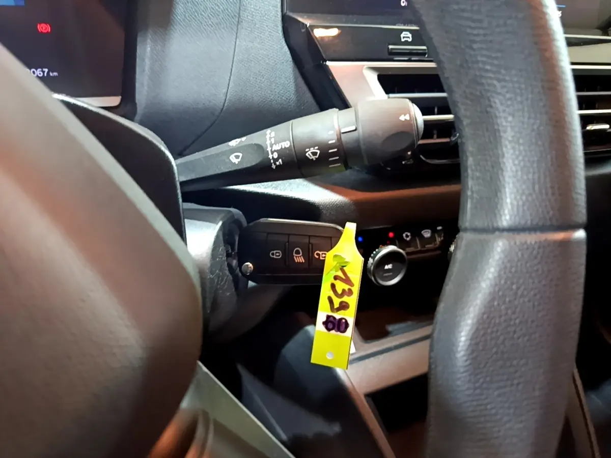 Gros plan intérieur sur la colonne de direction et commandes derrière le volant d'une Citroën C4 gris foncé, version 2021.