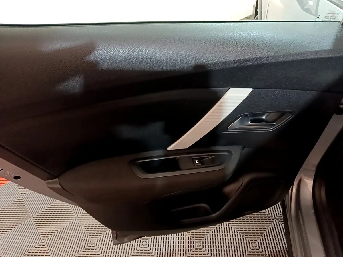 Vue intérieure du panneau de porte arrière droite de la Citroën C4 gris foncé avec poignée et bouton de verrouillage.