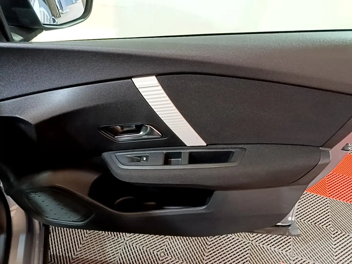 Intérieur de la porte avant gauche d'une Citroën C4 gris foncé, avec poignée noire et insert décoratif argenté.