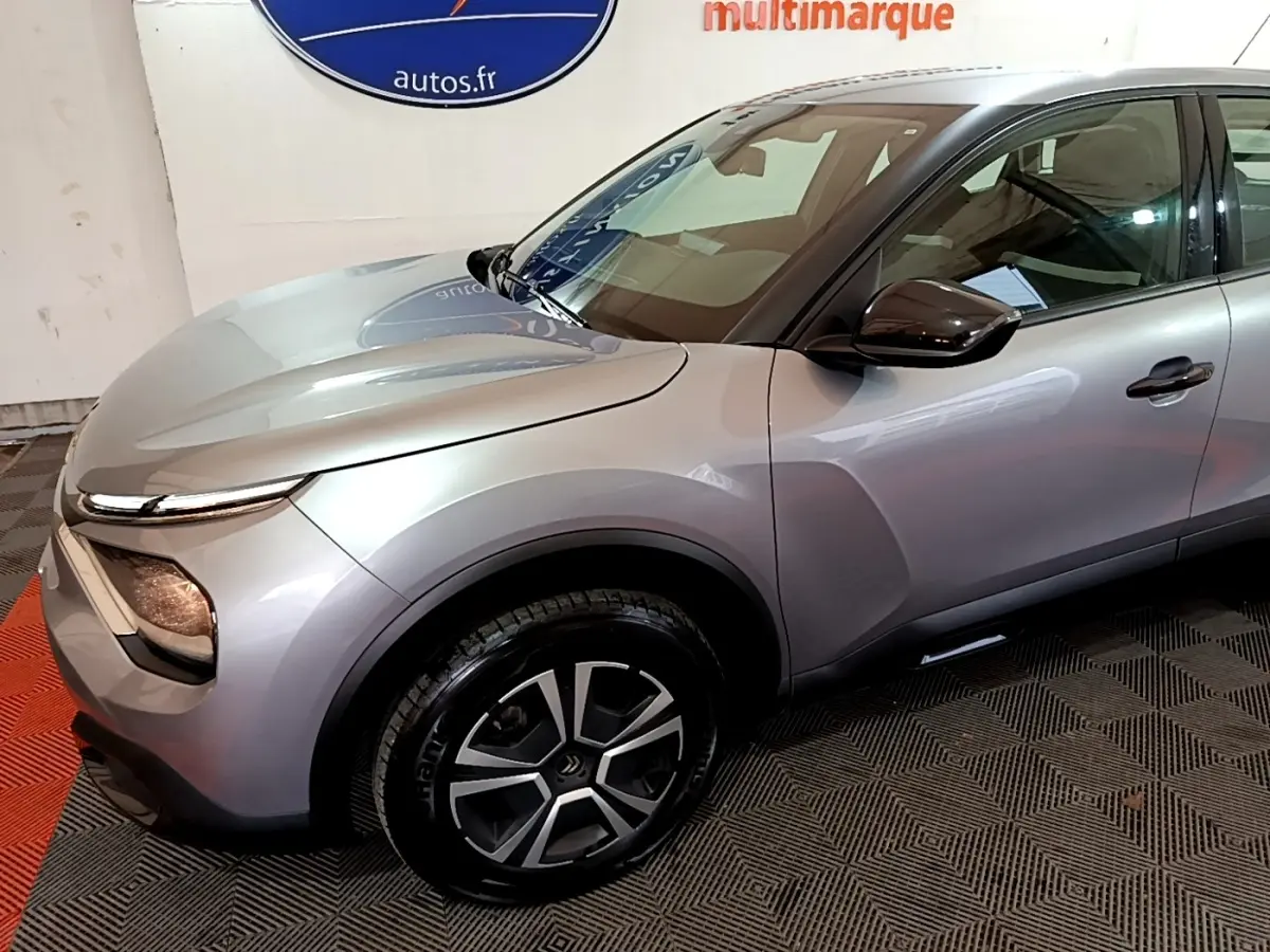 Vue 3/4 avant droit d'une Citroën C4 gris foncé avec jantes noires et phares LED distinctifs.