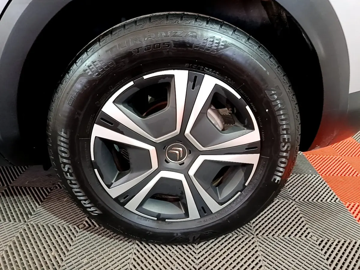 Gros plan sur la roue avant droite d'une Citroën C4 gris foncé, avec jante alliage et pneu Bridgestone.