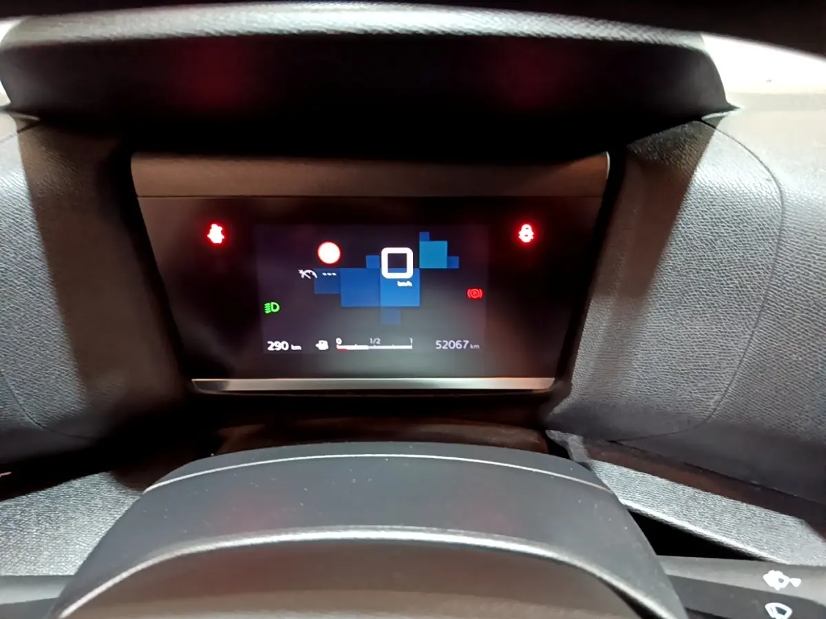 Tableau de bord numérique de Citroën C4 gris foncé, affichant 52 067 km et indicateurs lumineux rouges.