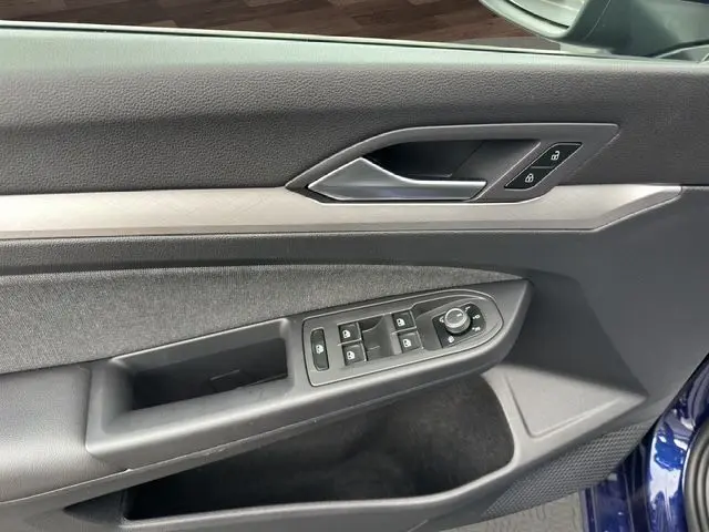 Vue rapprochée de la porte avant gauche intérieure de la Volkswagen Golf VIII bleu, avec commandes des vitres et verrouillage.