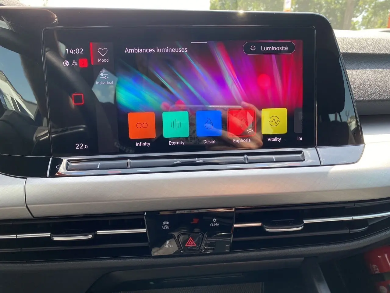 Écran tactile central de la Volkswagen Golf VIII bleu, affichant les ambiances lumineuses dans l'habitacle noir.