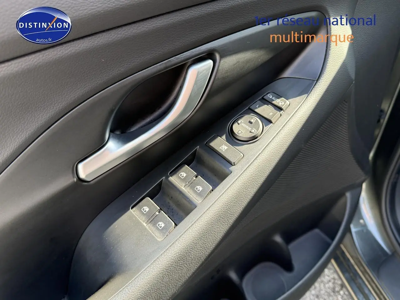 Gros plan sur la commande des vitres côté conducteur d'une Hyundai i30 gris anthracite 2024.