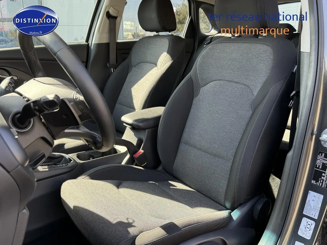 Intérieur avant droit de la Hyundai i30 2024 gris anthracite, sièges tissu avec volant cuir multifonction visible.