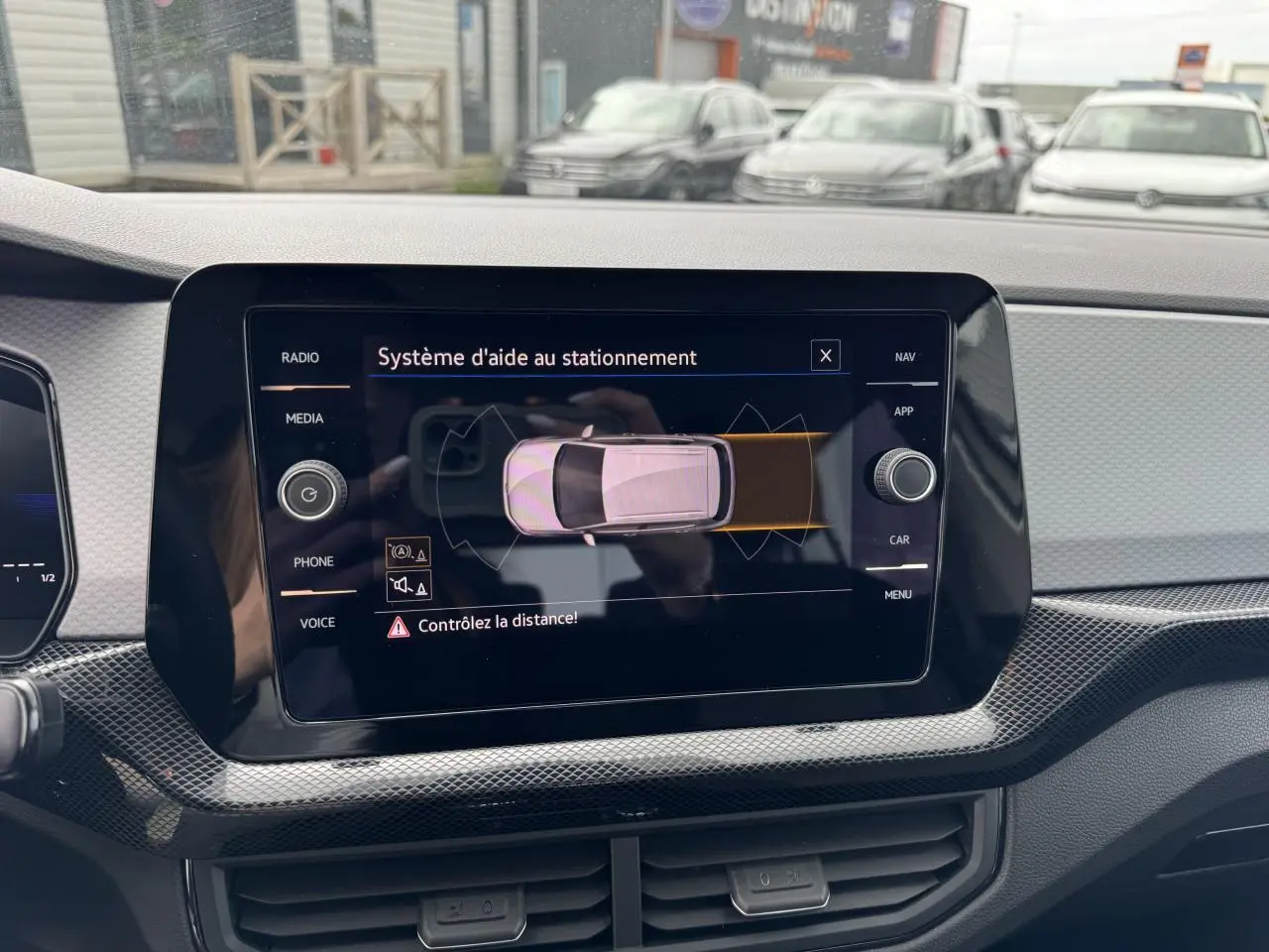 Écran tactile du système d'aide au stationnement dans un Volkswagen T-Cross gris Ascot, vue intérieure avant.