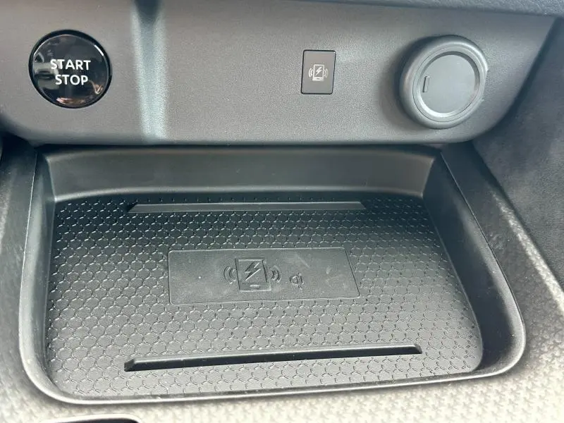 Plateau de recharge sans fil noir dans l'habitacle du Nissan Qashqai e-POWER 2025 avec bouton Start/Stop visible.