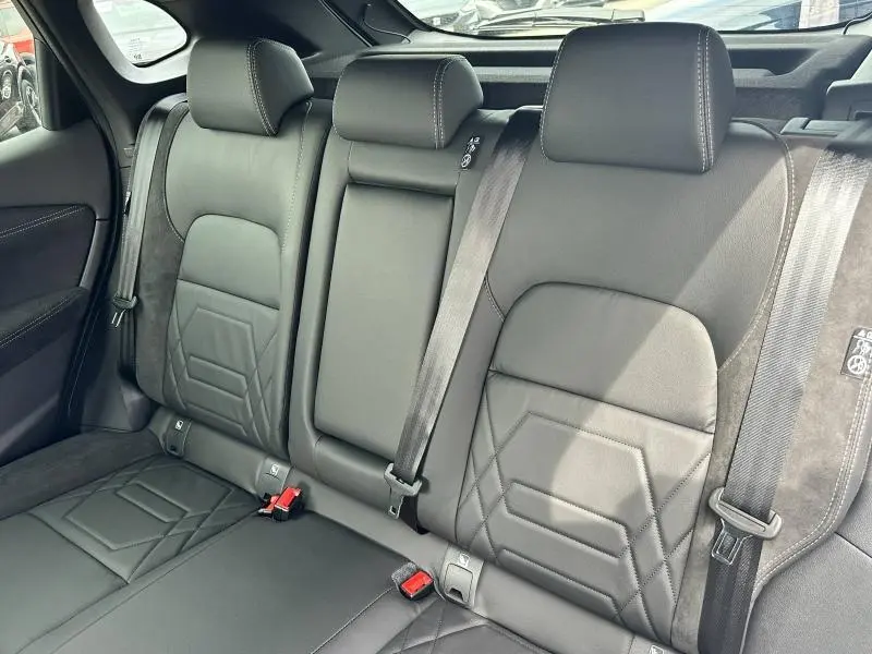 Vue intérieure arrière du Nissan Qashqai e-POWER 2025, sièges en cuir noir avec surpiqûres et ceintures de sécurité visibles.