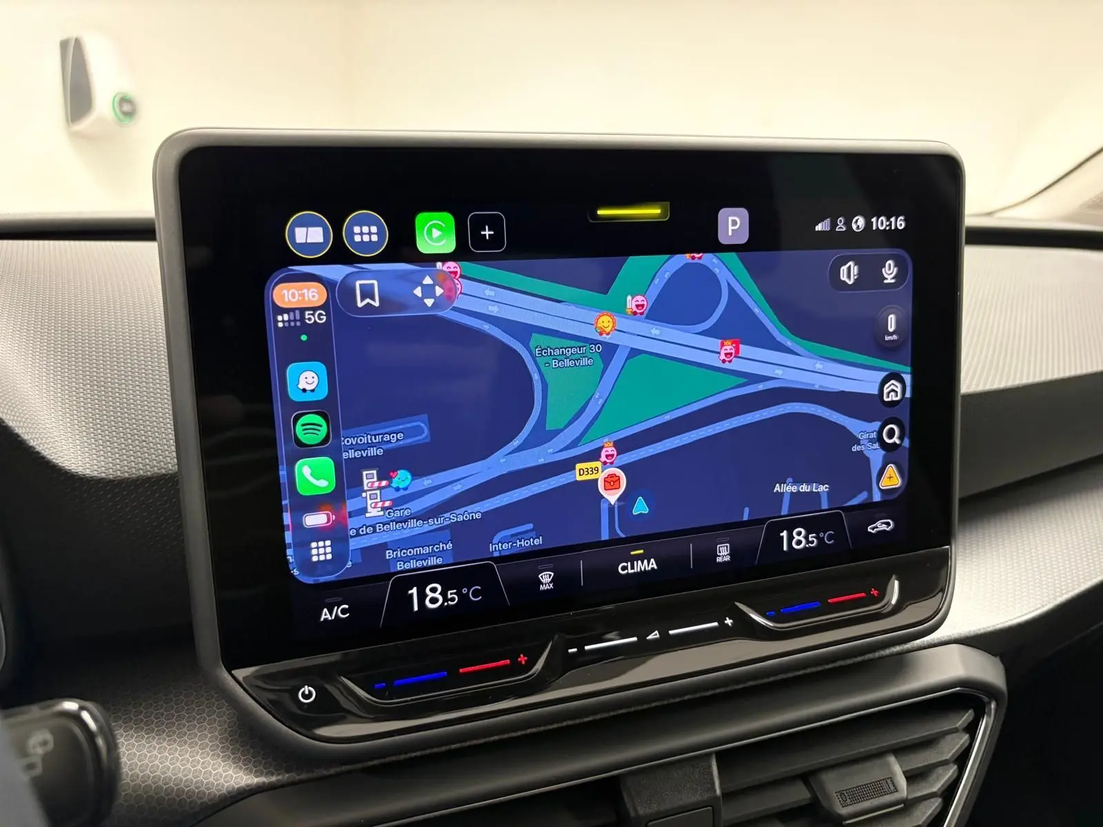 Écran tactile central du SEAT LEON 1.5 eTSI Hybrid 2025 affichant la navigation avec commandes climatiques intégrées.