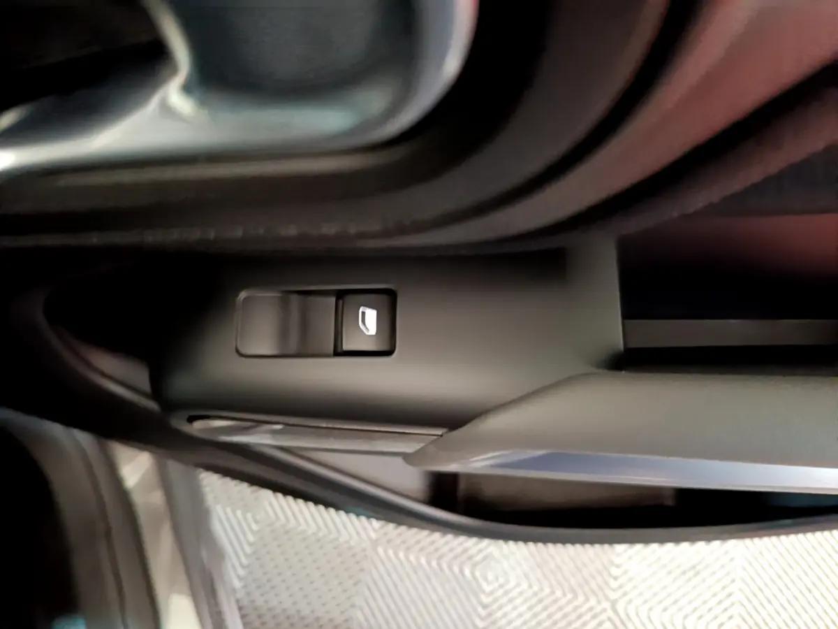 Gros plan sur le bouton de verrouillage des vitres côté conducteur d’un Citroën C5 Aircross gris foncé, intérieur noir.