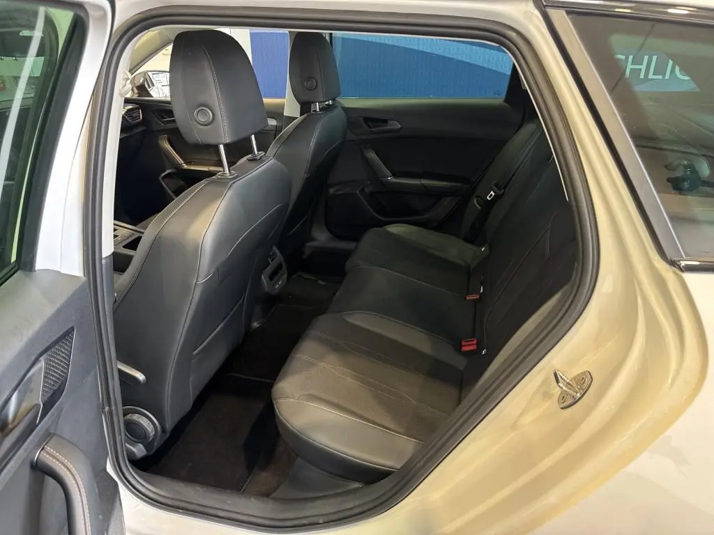 Vue intérieure arrière côté gauche de la CUPRA LEON ST blanche 2024, sièges arrière en cuir noir et finition soignée.