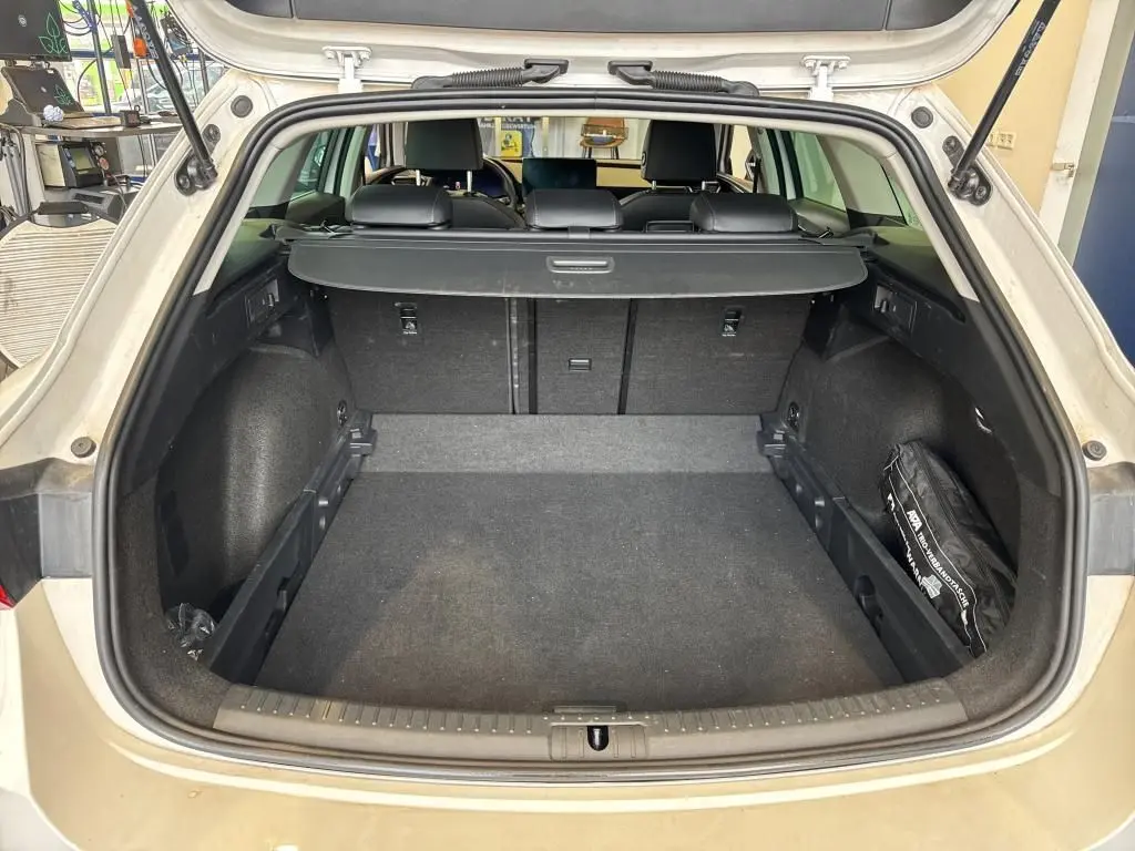 Coffre ouvert vu de l'arrière d'une CUPRA LEON ST blanche 2024, avec cache-bagages et intérieur noir.