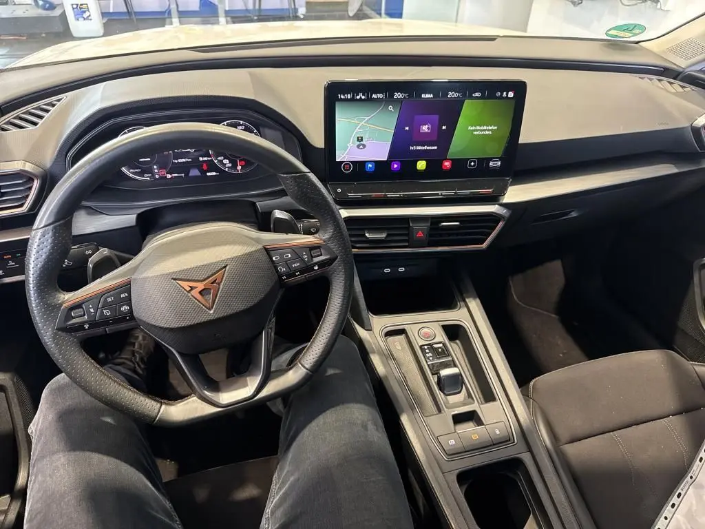 Vue intérieure avant centrée sur le volant noir et le tableau de bord avec écran tactile du CUPRA LEON ST 2024.