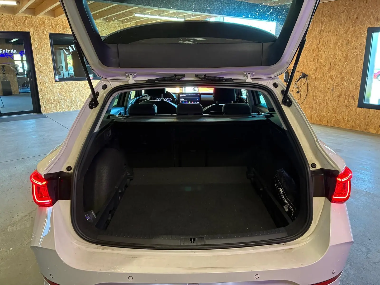 Vue arrière ouverte du coffre d'une CUPRA Leon ST blanche 2024, avec feux arrière allumés en intérieur.